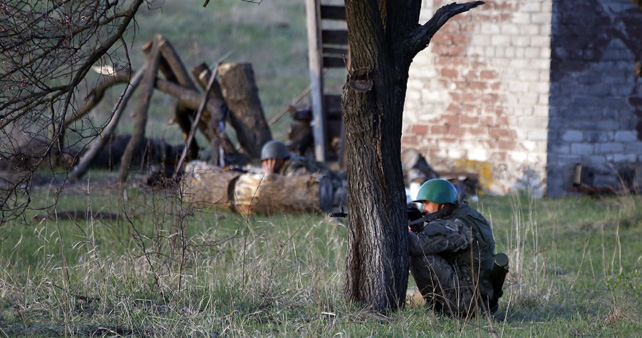 Un soldado ucraniano apunta con su rifle detrás de un árbol frente a una base aérea ucraniana en Kramatorsk.