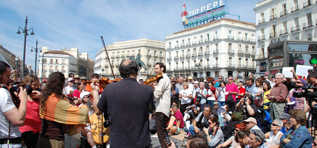 Varias personas escuchando la actuación de la Solfónica en la Puerta del Sol