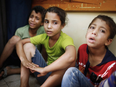 Tres niños palestinos, conmocionados tras sobrevivir a un bombardeo israelí. REUTERS/Finbarr O'Reilly
