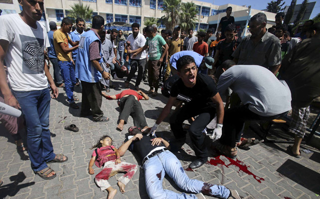 Varios palestinos lloran la muerte de los alcanzados por un misil israelí que atacó este domingo una escuela de la ONU en el sur de Gaza. REUTERS/Ibraheem Abu Mustafa