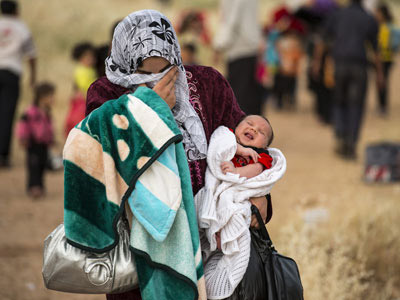 Una joven cruza la frontera de Siria con su hijo en brazos de apenas un mes. ACNUR