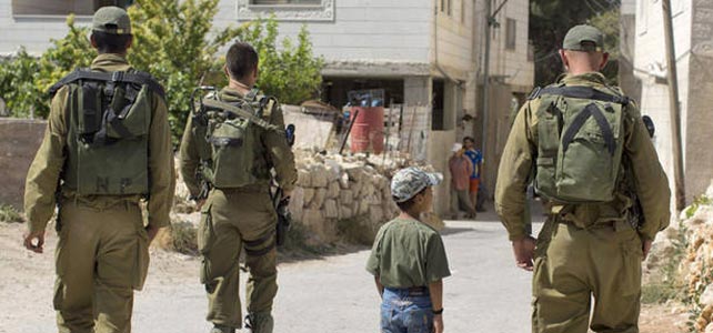 Un nio Palestino camina rodeado por soldados del Ejrcito israel.