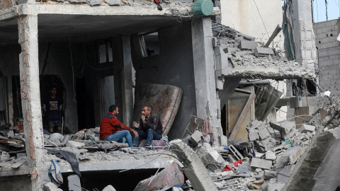 Dos palestinos conversan sentados dentro de un edificio destruido por los bombardeos israelíes, en Nuseirat, en el centro de la Franja de Gaza.