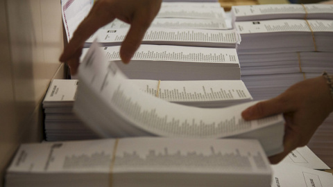 Un funcionario coloca los mazos de papeletas en un colegio electoral en Madrid. REUTERS