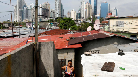 Una mujer sale de su vivienda en una barriada popular en la ciudad de Panamá, con el distrito financiero al fondo. REUTERS/Carlos Jasso