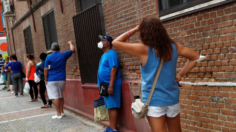 Personas guardan cola para recibir alimentos donados en la parroquia de San Ramón Nonato, de Madrid, durante el estado de alarma por la pandemia por coronavirus. REUTERS / Susana Vera