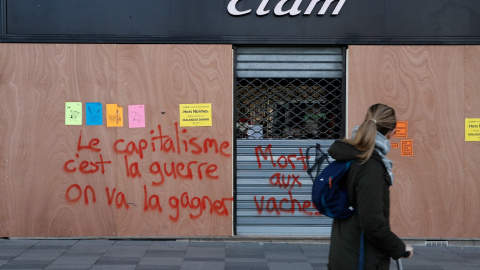 Una joven pasa junto a una pintada en París, que dice "Nosotros ganaremos la guerra contra el capitalismo". AFP/Francois Guillot