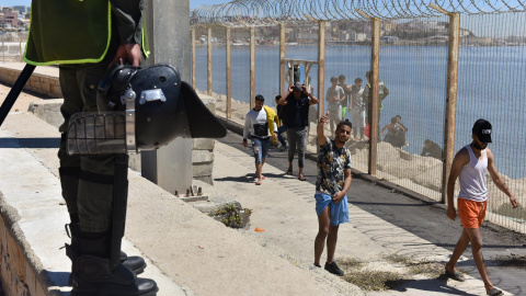  La policía antidisturbios marroquí monta guardia para evitar el paso de personas en la carretera entre Fnidq cerca de la ciudad española de Ceuta, el 19 de mayo de 2021.- EFE