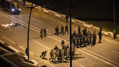  La Policía marroquí se forma mientras migrantes protestan contra que se les impida cruzar la frontera en la ciudad norteña de Fnideq, cerca de la frontera entre Marruecos y el enclave español de Ceuta, en el norte de África, el 19 de mayo de 2021.- 