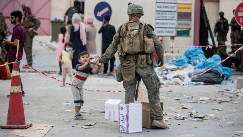 Un marine del Ejército estadounidense entrega un paquete de comida a un niño en el aeropuerto de Kabul. REUTERS