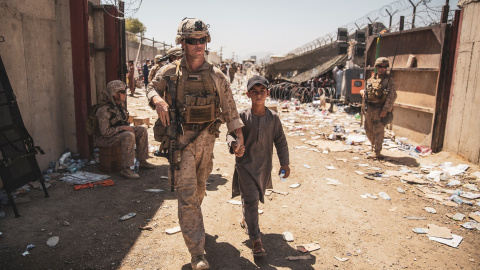 Un marine estadounidense acompaña a un menor junto a su familia para su evacuación, en el aeropuerto de Kabul (Afganistán). REUTERS