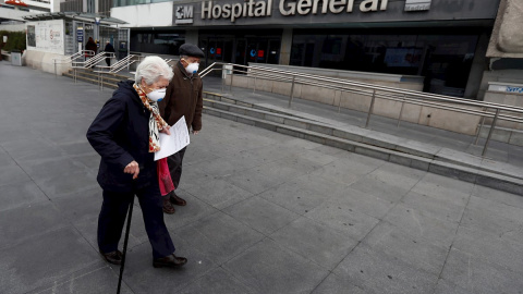 Una pareja de ancianos pasa ante el Hospital de La Paz, en Madrid. EFE/Mariscal