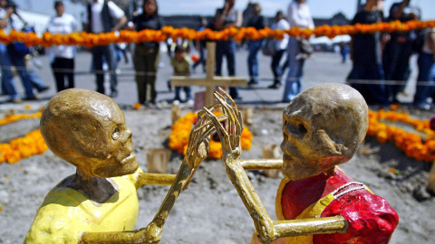  Transeuntes observan una Ofrenda de Muertos dedicada a los niños en el zócalo de Ciudad de Mexico, el 31 de octubre de 2003, como parte de las celebración del "Día de Muertos".- AFP