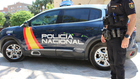 Un agente de la Policía Nacional junto a un vehículo policial. EFE