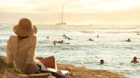 Imagen de una mujer mirando al mar mientras muchas personas disfrutan. Foto: dpung / Pixabay