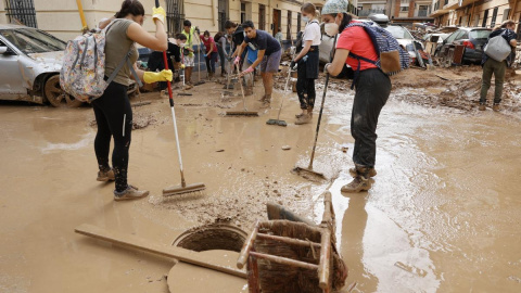 Vecinos y voluntarios colaboran en las labores de limpieza en la localidad de Paiporta este sábado tras el paso de la DANA.- EFE, Biel Aliño.