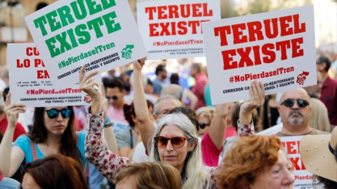  Una manifestante exhibe sendos carteles con el lema "Teruel existe" durante una manifestación convocada en València para reivindicar la necesidad de "no perder el tren" del Corredor Cantábrico-Mediterráneo,en la que han pedido inversiones en el tramo