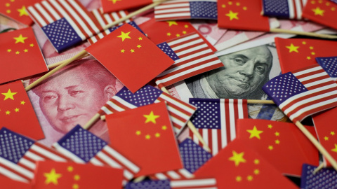 Billetes de dólar y de yuan, entre banderas de EEUU y de China.. REUTERS/Jason Lee/Illustration