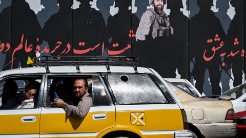  Un hombre mira por la ventanilla de un automóvil mientras los viajeros avanzan por una carretera en Kabul el 5 de septiembre de 2021. A las pocas semanas de que los talibanes tomaron la capital, muchas de las obras de arte callejero han sido pintadas, r