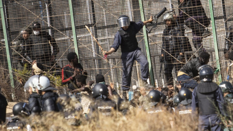 Un agente marroquí golpea desde territorio español con un palo a los migrantes que lograron saltar la valla de Melilla. -Javier Bernardo