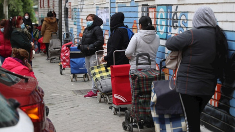  Varias personas esperan en la fila para recoger alimentos proporcionados por la Asociación de vecinos de Aluche. EFE.