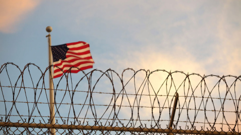  16 de octubre de 2018, Cuba, Bahía de Guantánamo: Una bandera de Estados Unidos ondea al viento detrás de una cerca de alambre de púas en el campo de detención de la Bahía de Guantánamo. Foto: Maren Hennemuth / dpa