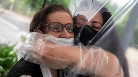  Una dona abraça la seva mare a través d'una cortina de plàstic, per protegir-la d'una possible infecció per coronavirus a una residència a la vora de València, el junys del 2020 -- JOSE JORDAN / AFP