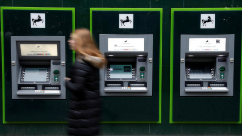 Una mujer pasa junto a los cajeros automáticos de una sucursal de Lloyds Bank en Manchester. REUTERS/Phil Noble