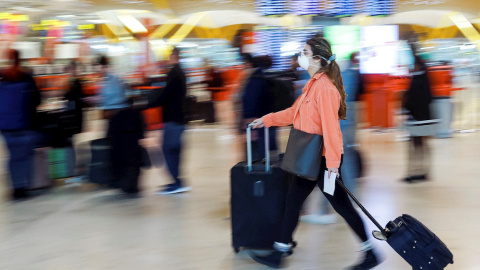 Viajeros protegidos con mascarillas este jueves en el Madrid Barajas Adolfo Suárez. La declaración del coronavirus como pandemia por parte de la OMS llevó este miércoles a extremar las medidas en América, donde EE.UU. suspendió por 30 días los viaj