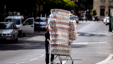 Un trabajador transporta numerosos rollos de papel higiénico en un carro de la compra dirección a un comercio en el centro de Málaga. - EFE