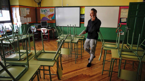 Un docente habla por su teléfono móvil en un aula desierta en un colegio público de Madrid.. - EFE