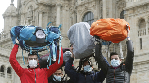 13/03/2020.- Peregrinos muestran sus mochilas mientras se protegen con mascarillas al terminar el Camino a pesar de la crisis del coronavirus. / EFE - LAVANDEIRA JR