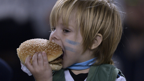 Un niño argentino se come una hamburguesa. Juan MABROMATA. AFP