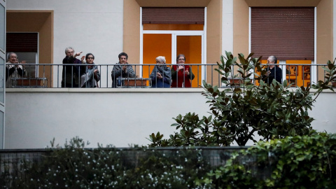 Un grupo de jubilados aplaude aplaude desde un balcón para agradecer el trabajo de los sanitarios que luchan contra la pandemia de coronavirus, en la decimoquinta jornada de estado de alarma. EFE/Javier Etxezarreta