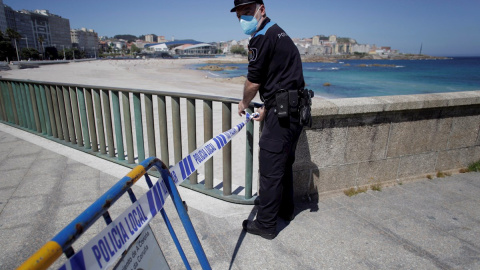 26/05/2020.- Un agente de la Policía Local de A Coruña delimita este martes con cinta policial una de las casetas de socorrismo que ha sido instalada en el paseo marítimo de la ciudad, a la altura de la coraza del Orzán en A Coruña. EFE/Cabalar