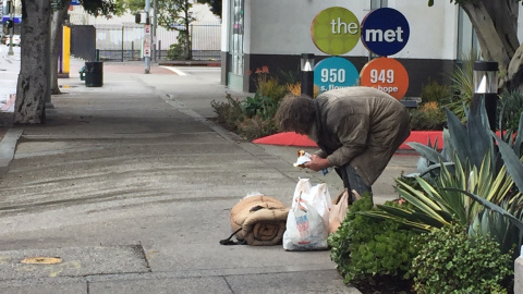 Un indigente de mediana edad comiendo en mitad de una céntrica calle de Los Ángeles. / Aitana Vargas