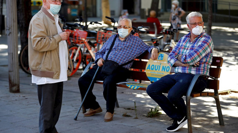 Tres hombres conversan en una plaza de Barcelona. EFE