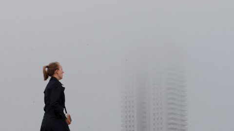 Una persona pasa junto a un edificio envuelto en niebla en Valencia. EFE