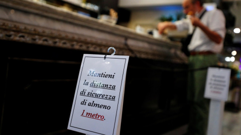 Un cartel en la barra de un bar en Roma pide que se guarde una distancia mínima de seguridad por la pandemia del coronavirus. REUTERS/Guglielmo Mangiapane