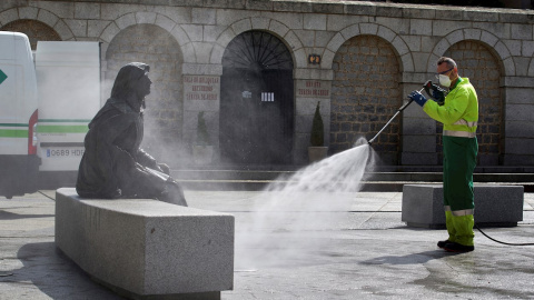 Un operario trabajando en labores de desinfección junto a la escultura de Santa Teresa de Jesús, este sábado en Ávila, durante la quinta semana de confinamiento debido al estado de alarma decretado por el gobierno para frenar la pandemia del COVID 19.