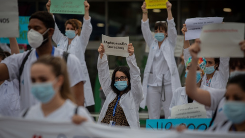 Decenas de miembros del personal sanitario protegidos con mascarilla sostienen carteles durante la concentración de sanitarios en el Día Internacional de la Enfermería a las puertas del Hospital Vall d'Hebron, en Barcelona. Europa Press / Archivo