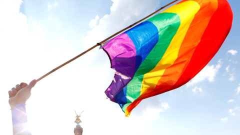 Una persona sostiene una bandera LGBT frente a la Columna de la Victoria de Berlín durante el desfile anual del Orgullo LGBT. REUTERS / Axel Schmidt / Archivo