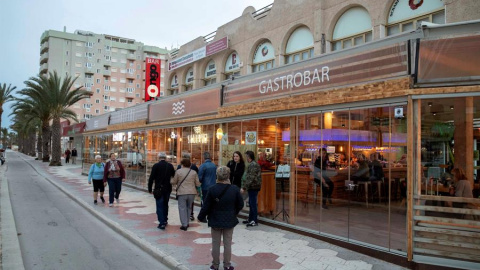 Varias personas pasean junto a un restaurante esta tarde en La Gran Vía de la Manga del Mar Menor. EFE/Marcial Guillén