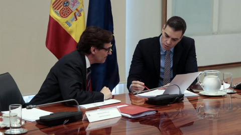 Fotografía facilitada por Moncloa que muestra al presidente del Gobierno, Pedro Sánchez (d) mientras conversa con el ministro de Sanidad, Salvador Illa (i) durante la videoconferencia de presidentes autonómicos tras haber anunciado una nueva prórroga 