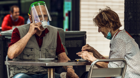 Un home amb un plàstic protector beu cafè en una terrassa d'un bar de la Plaça Catalunya de Barcelona. Matthias Oesterle/ZUMA Wire/dpa