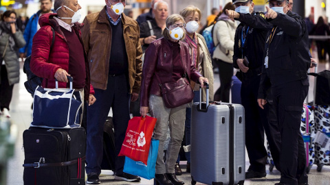 16/03/2020.- Un grupo de pasajeros atiende las indicaciones de agentes de la Policía Nacional en el Aeropuerto Internacional de Málaga. / EFE - JORGE ZAPATA