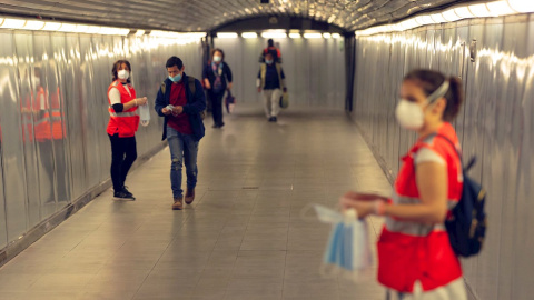 GRAFCAT5817. BARCELONA, 04/05/2020.- Voluntarias de la Cruz Roja reparte mascarillas en el Metro de Barcelona, este lunes, primer día en el que el uso de mascarillas en el transporte público es obligatorio, en el inicio de la fase 0 del plan de desescal