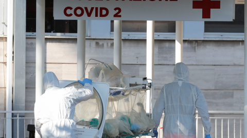 Dos sanitarios trasladan a un enfermo con coronavirus a un hospital en Roma./ REMO CASILLI (REUTERS)