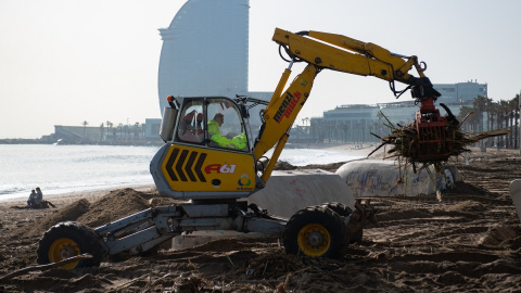 Un operario recoge parte de los desperfectos provocados por el temporal 'Gloria' en la playa de Barcelona. (Josep Lago-AFP)