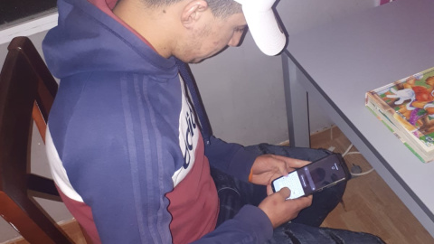 Ahmed, en casa, usando el teléfono para conectarse con su familia